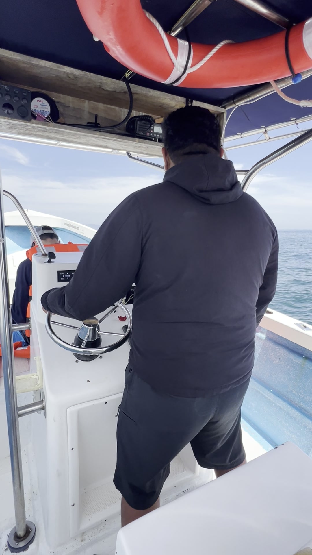 Capitán de Pípilas al timón de una lancha, mar abierto al fondo.